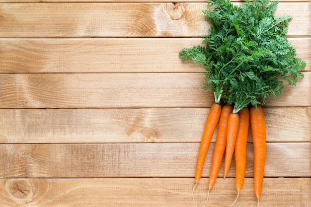 Verdura fresca della carota con i fogli sui precedenti di legno.