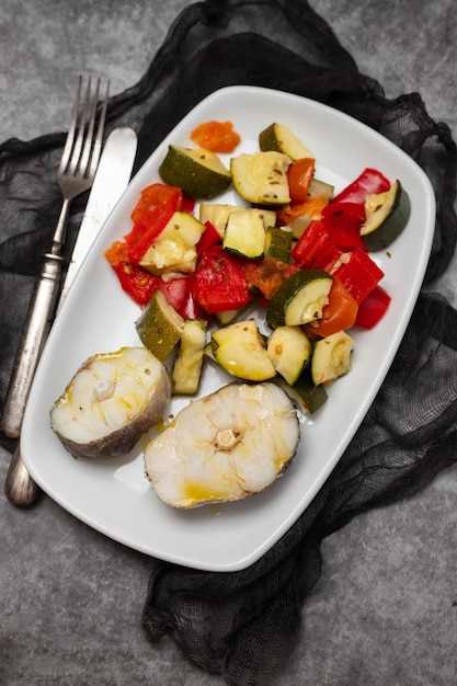 Verdure al forno con pesce bollito sulla piastra bianca