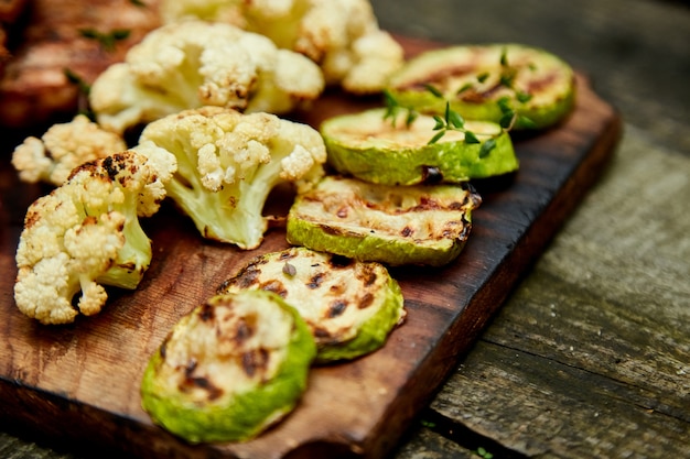 Verdure arrostite del cavolfiore e dello zucchini su fondo di legno.