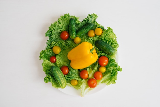 Verdure biologiche fresche su un piatto su un tavolo o uno sfondo bianco