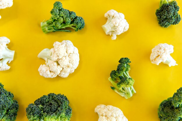 Verdure, broccoli e cavolfiori su sfondo giallo.