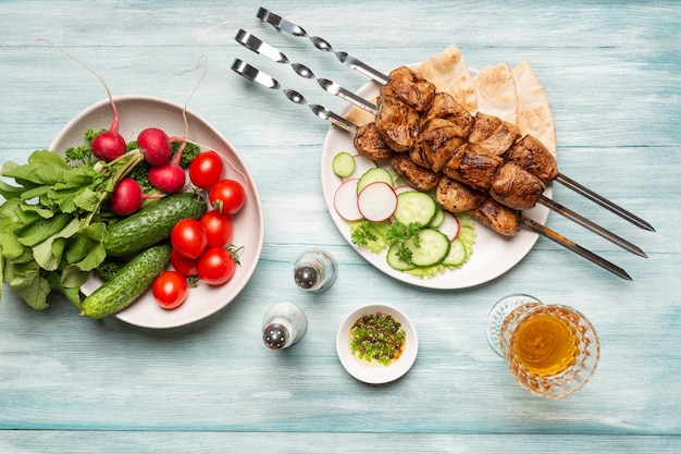 Verdure di shish kebab fatte in casa appetitose e bicchiere di vino vista dall'alto su uno sfondo di legno blu