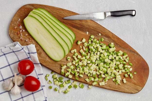 Verdure di zucchine affettate su un tagliere di legno pomodori e aglio