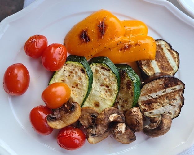 Verdure e funghi cucinati sul primo piano bianco del piatto