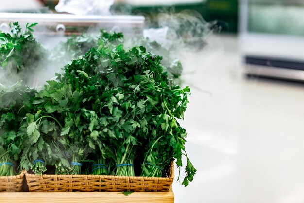 Verdure ed erbe verdi vengono soffiate con vapore idratante sul primo piano del bancone del supermercato