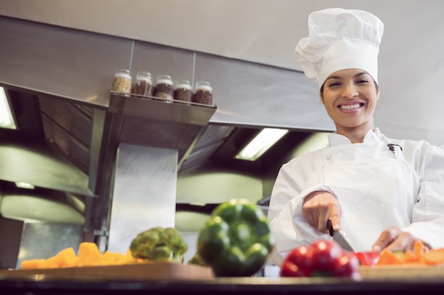 Verdure femminili sorridenti di taglio del cuoco unico in cucina