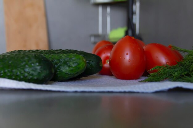 Verdure fresche cetrioli pomodori e verdure con aneto e prezzemolo giacciono sulla superficie grigia della cucina su un asciugamano di lino