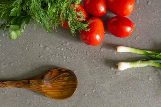 Verdure fresche e fragranti e un cucchiaio di bambù giacciono sulla cucina grigia