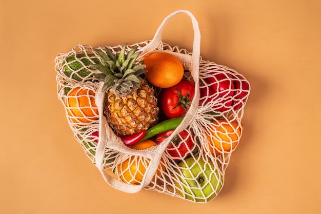 Verdure fresche e frutta in maglia di borsa, vista dall'alto.