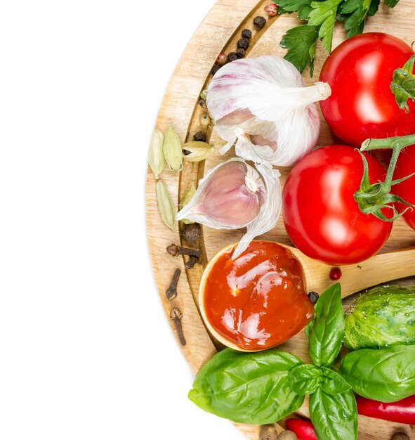 Verdure fresche e spezie su una tavola rotonda di legno isolata su fondo bianco