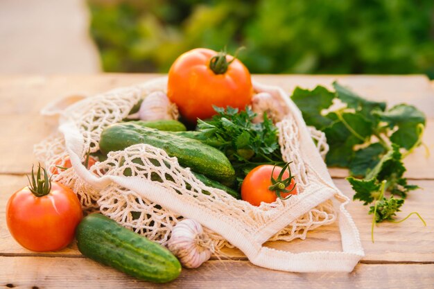 Verdure fresche e succose prodotti in una borsa della spesa riutilizzabile un sacchetto di corda fatto di materiali riciclati su un tavolo di legno in giardino Vegetarianismo Nessuna plastica Stile di vita ecologico