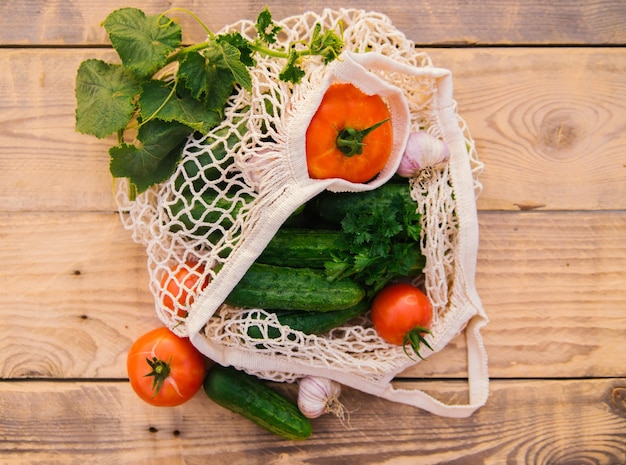 Verdure fresche e succose prodotti in una borsa della spesa riutilizzabile un sacchetto di corda fatto di materiali riciclati su un tavolo di legno in giardino Vegetarianismo Nessuna plastica Stile di vita ecologico