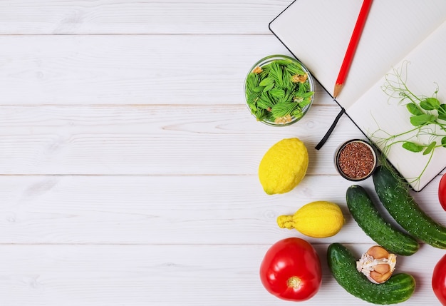 Verdure fresche, frutta e spezie con libro aperto sul tavolo bianco