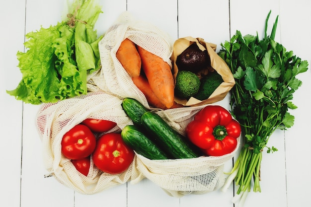 Verdure fresche in sacchetti di eco sulla tavola bianca