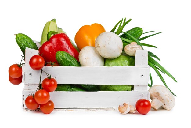 Verdure fresche in una scatola di legno dipinta isolata su fondo bianco