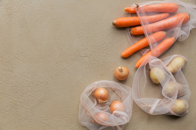 Verdure fresche patate, cipolle, carote confezionate in un sacchetto a rete riutilizzabile con coulisse. Rifiuto dal pacchetto di plastica. Imballaggio ecologico.