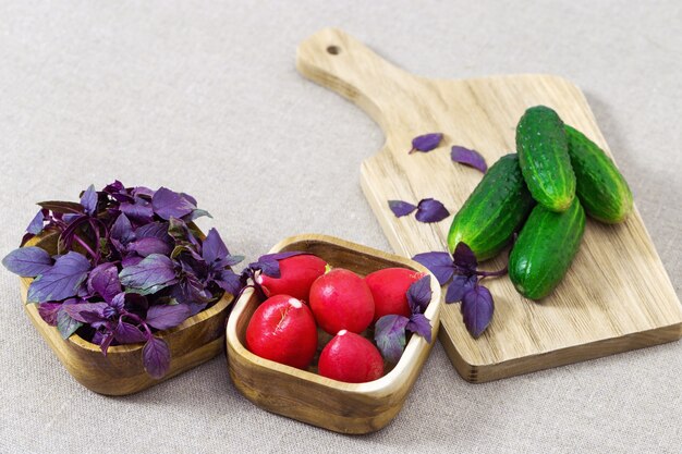 Verdure fresche per cucinare insalata di verdure. Cetrioli, ravanelli, basilico viola sul tavolo. Copia spazio.