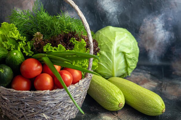 Verdure fresche per insalata in un cesto Pomodori e cetrioli con zucchine e cavoli con aneto Benefici e vitamine del raccolto primaverile Su sfondo scuro