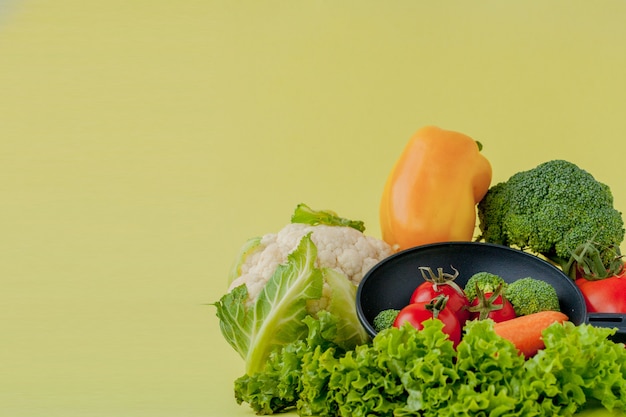 Verdure fresche su padella su sfondo giallo. Vegan e concetto sano