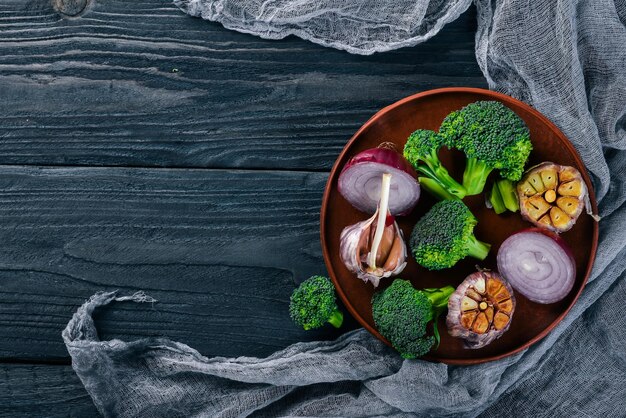 Verdure fresche su un piatto di argilla su uno sfondo di legno Vista dall'alto Spazio libero per il testo