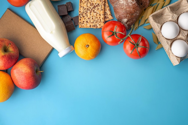 Verdure, frutta, uova, generi alimentari su una vista dall'alto di sfondo blu. Set di prodotti freschi in un negozio online con consegna a domicilio e una sana varietà di cibo. Copia spazio.