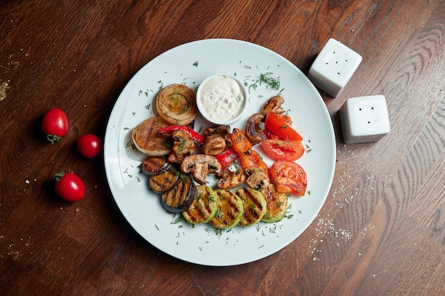 Verdure grigliate assortite - funghi, zucchine, peperoni, mais in un piatto di ceramica. Insalata tiepida vegetariana. Cibo salutare