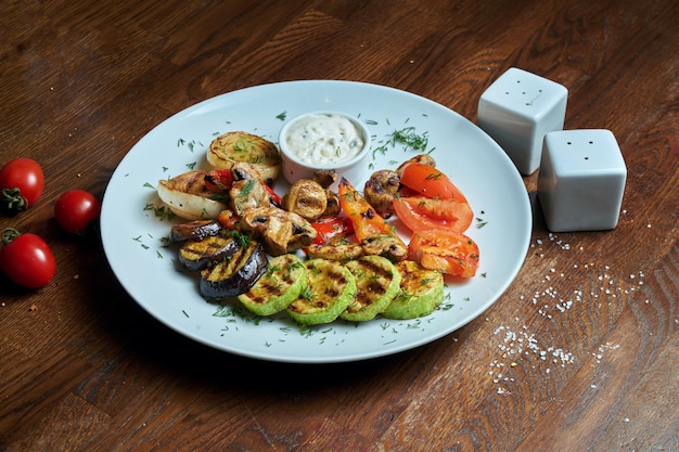 Verdure grigliate assortite - funghi, zucchine, peperoni, mais in un piatto di ceramica sulla a. Insalata tiepida vegetariana. Cibo salutare