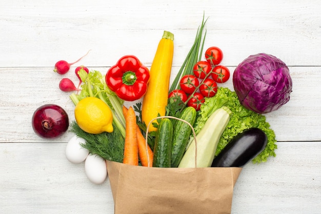 Verdure in un sacchetto di carta su un fondo di legno bianco. Fare la spesa in un supermercato o al mercato.