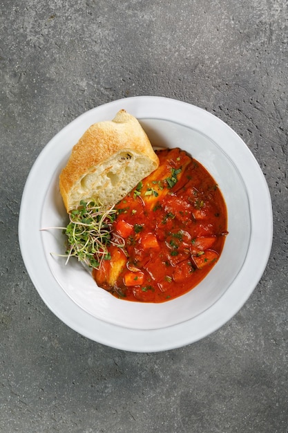 Verdure pronte da mangiare con pezzo di pane croccante in piatto bianco