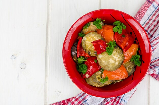 Verdure saltate con melanzane nel piatto rosso, cibo vegetariano