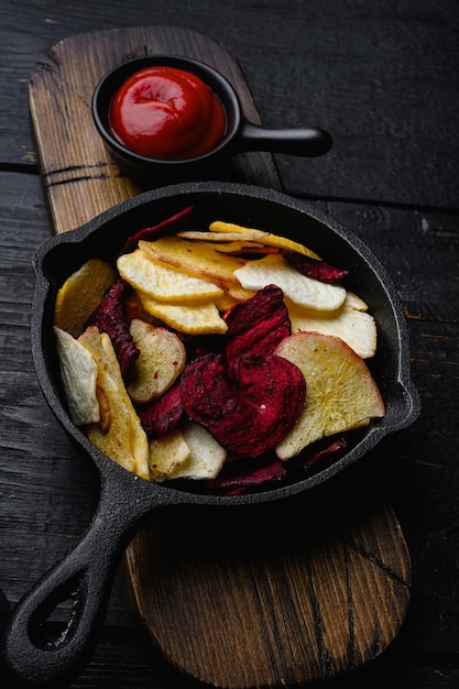 Verdure secche chips su tavola di legno nero sullo sfondo