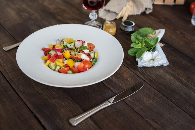 Verdure variopinte fresche su un piatto bianco su un fondo di legno scuro