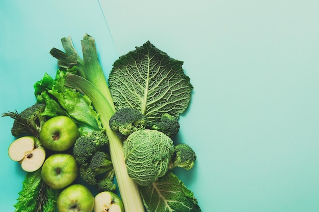 Verdure verdi e frutta. Dieta, disintossicazione e concetto di cibo sano - vista dall'alto piatta di pasti vegetariani su sfondo blu brillante. Ingredienti per insalata