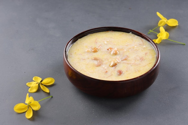 Vermecelli Payasam o Kheer, piatto dolce principale dell'India meridionale preparato durante occasioni speciali con vermicelli, latte, zucchero e noci secche e splendidamente organizzato con fiori di doccia dorata nel dorso grigio