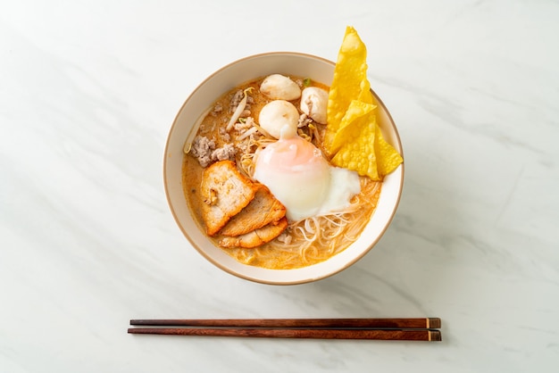 Vermicelli di riso con polpette, maiale arrosto e uova in zuppa piccante - Tom Yum Noodles