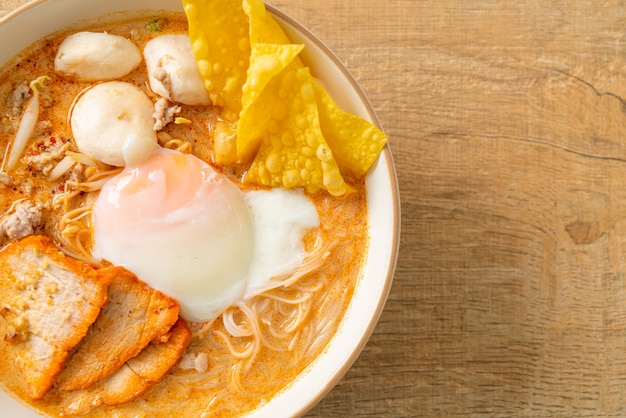 Vermicelli di riso con polpette, maiale arrosto e uova in zuppa piccante - Tom Yum Noodles