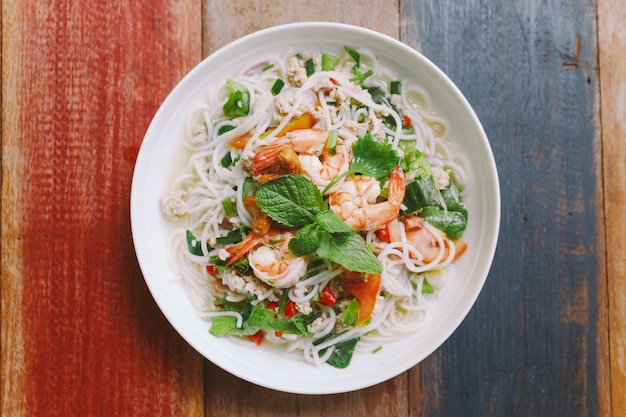 Vermicelli di riso piccante con gamberetti, carne di maiale macinata e peperoncino. Guarnire con foglie di menta.