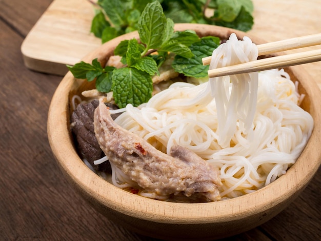 Vermicelli tailandesi mangiati con curry e verdure in ciotola di legno sul vecchio fondo della tavola di legno. spaghetto