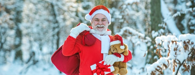 Vero babbo natale con berretto rosso che tira un grande sacco regalo rosso babbo natale con un'enorme borsa