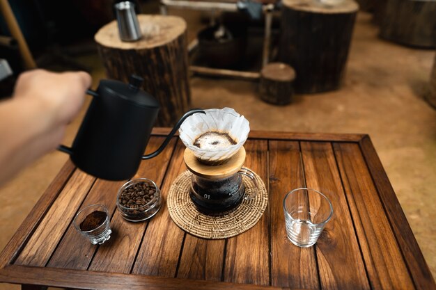 Versa l'acqua calda nel caffè., gocciola il caffè su un tavolo di legno a casa