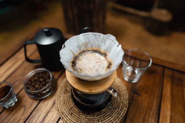 Versa l'acqua calda nel caffè., gocciola il caffè su un tavolo di legno a casa