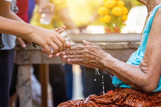 Versando acqua sulle mani di anziani riveriti e chiedendo benedizioni felici per il festival songkran