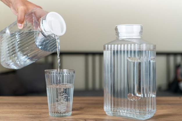 Versare a mano acqua pulita e pura in un bicchiere