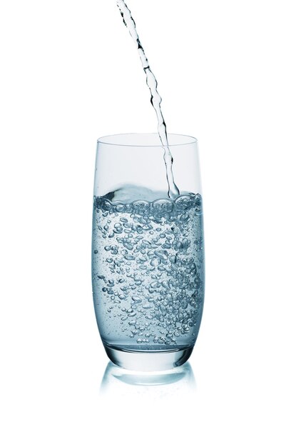 Versare acqua fresca in un bicchiere isolato su uno sfondo bianco