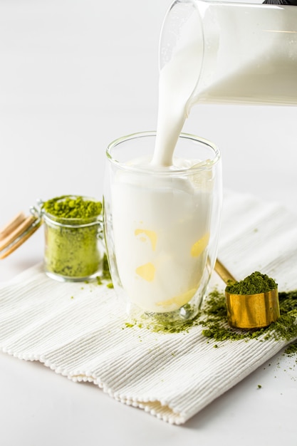 Versare il latte nel bicchiere per preparare il tè matcha latte