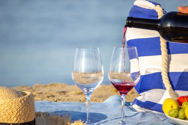 Versare il vino rosso nei bicchieri, con vista sul mare, picnic in riva al mare. Natura. Messa a fuoco selettiva