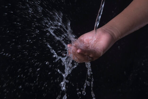 Versare l'acqua che spruzza a portata di mano con sfondo nero