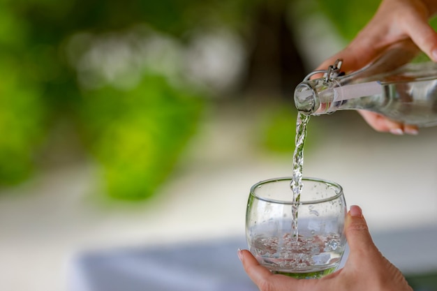 Versare l'acqua da una bottiglia in un bicchiere. Versare un bicchiere d'acqua. Un'immagine di versare un bicchiere d'acqua