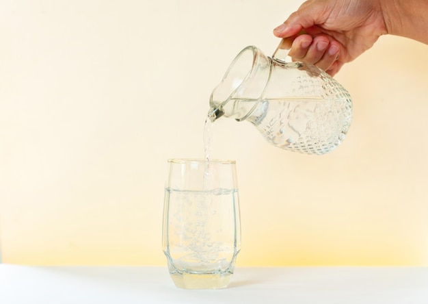 Versare l'acqua da una brocca di vetro a un bicchiere