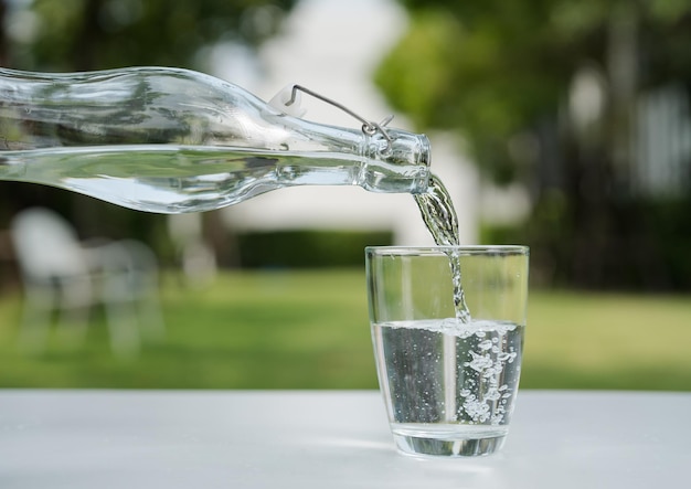 Versare l'acqua dalla bottiglia d'acqua nel bicchiere